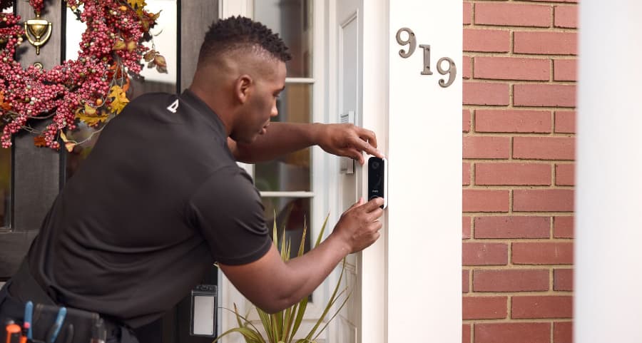 Vivint technician installing a video doorbell on the exterior of a home